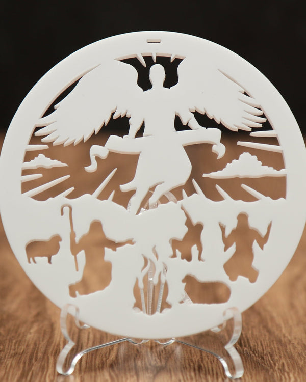 Decorative cut-out with angel and religious figures on a stand against a dark background