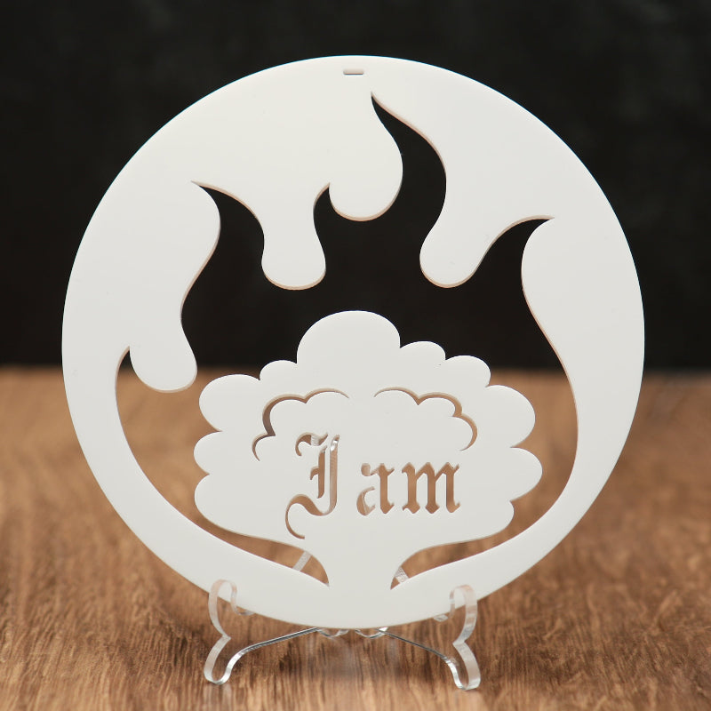 A white circular acrylic ornament  with flame and cloud cutouts, featuring the name 'I am' in a tree design, surrounded by a flame, displayed on a clear stand over a wooden surface.