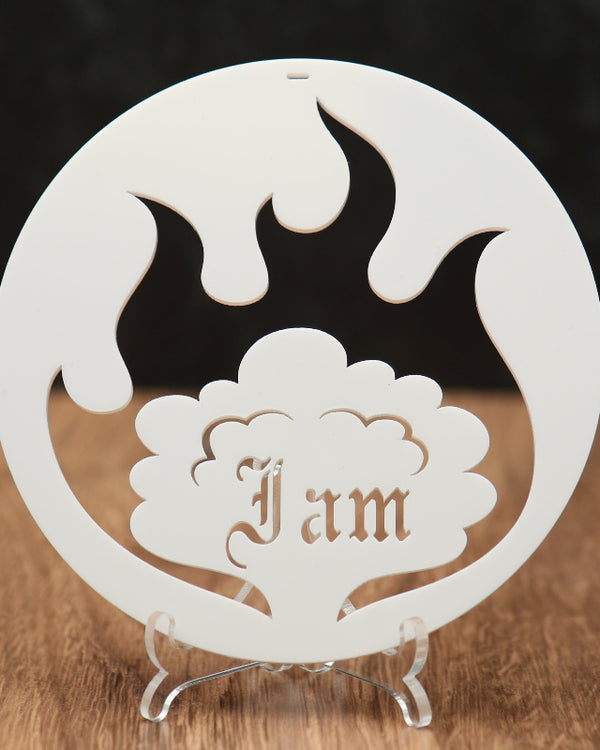 A white circular acrylic ornament  with flame and cloud cutouts, featuring the name 'I am' in a tree design, surrounded by a flame, displayed on a clear stand over a wooden surface.