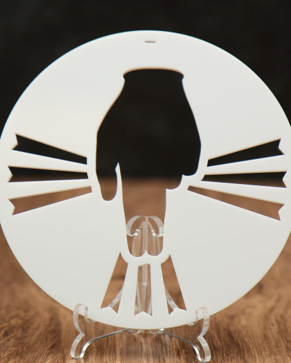 A white round acrylic ornament with a hand and rays coming out of the hand. 