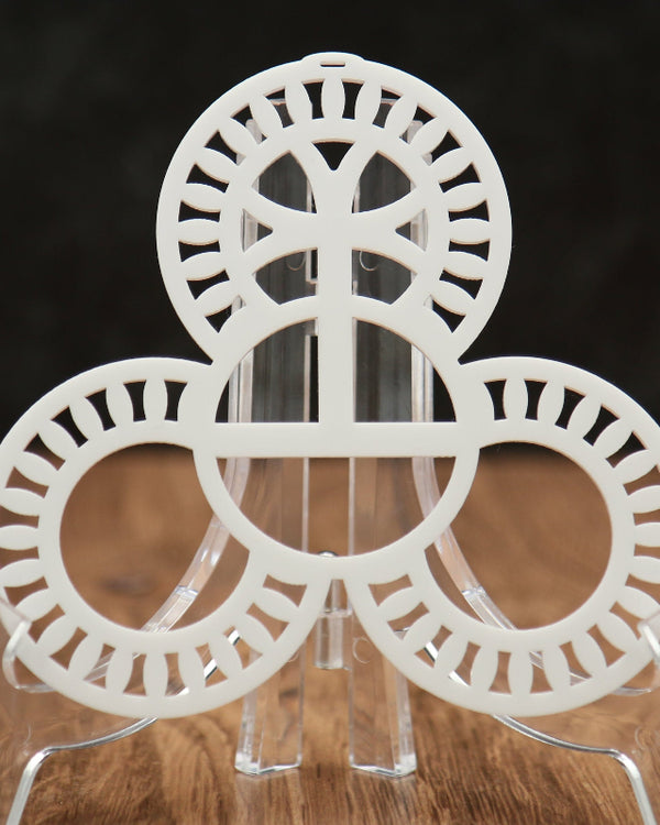 A white circular acrylic stand with three interlocking ring-like discs and clear acrylic legs, photographed on a wooden surface against a dark background.